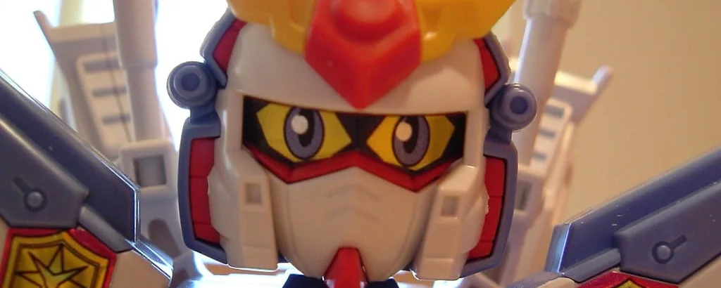 A close-up of an assembled Gundam model kit, its moulded head and shoulder armour filling the frame