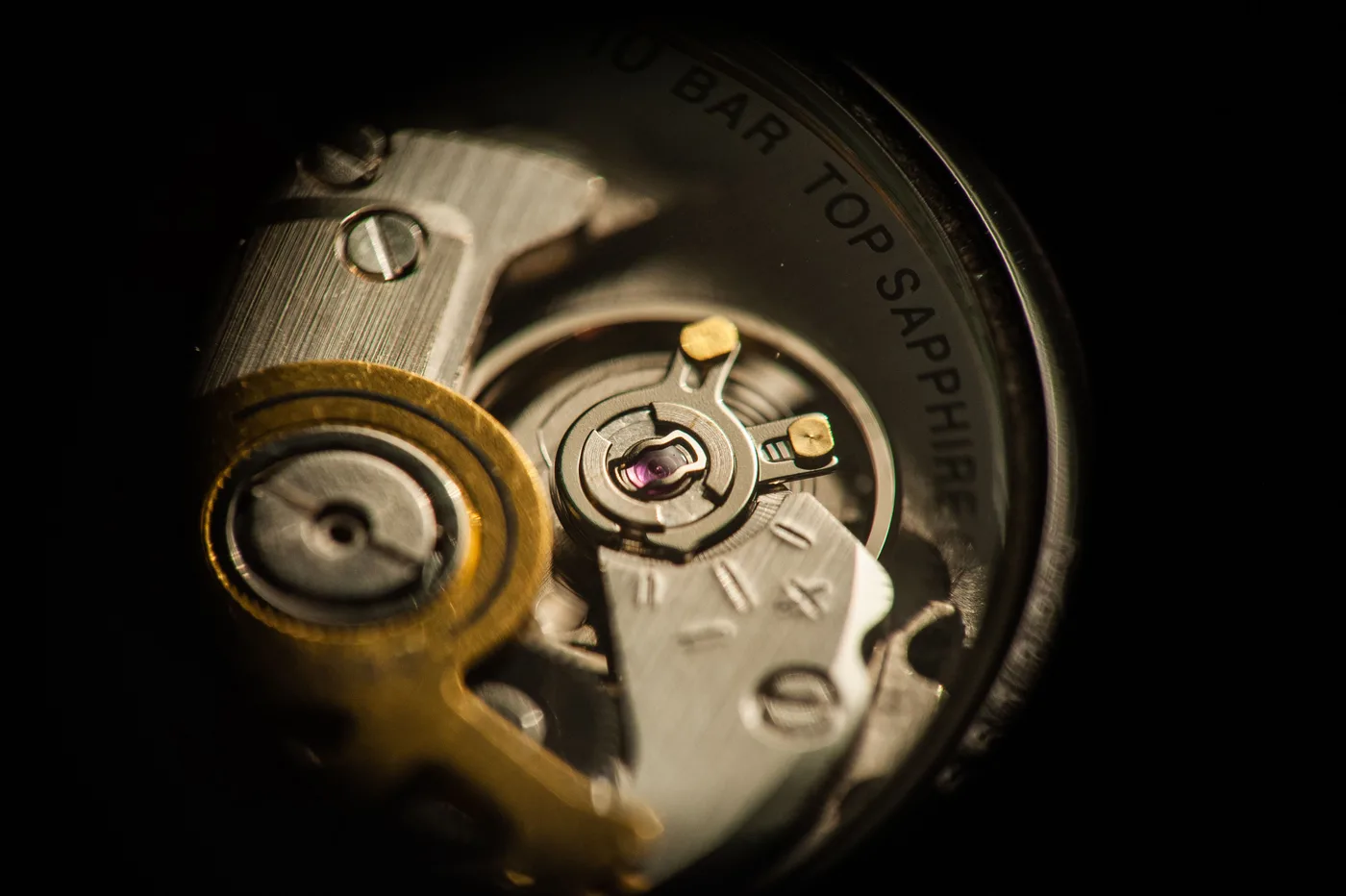 Macro detail of an exposed mechanical watch movement, showing gears and jewel bearings